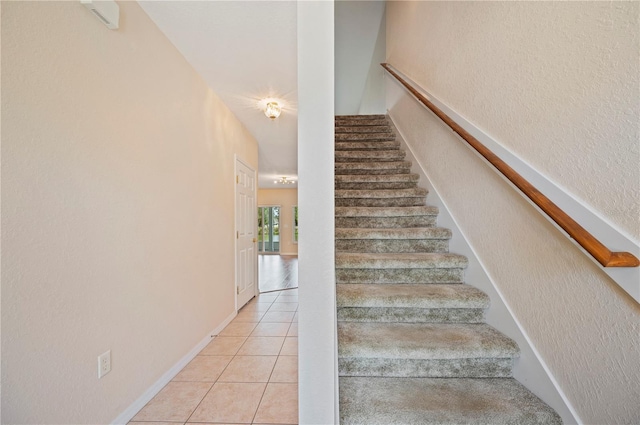 stairway featuring tile patterned flooring and a textured wall