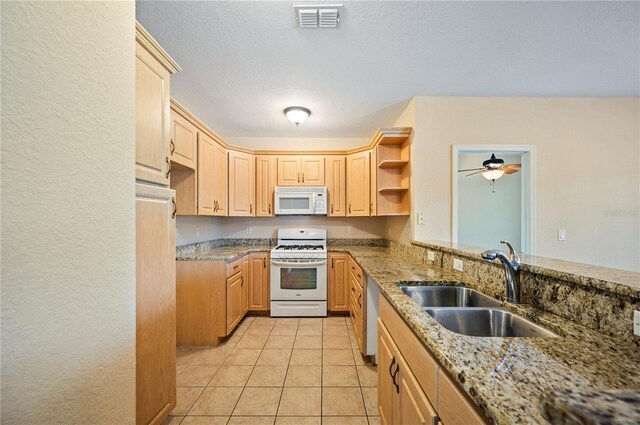 kitchen featuring a sink, light stone countertops, white appliances, and visible vents