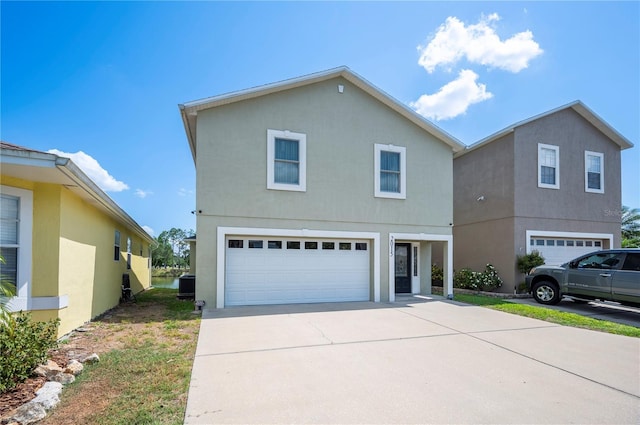 traditional-style home with an attached garage, concrete driveway, and stucco siding