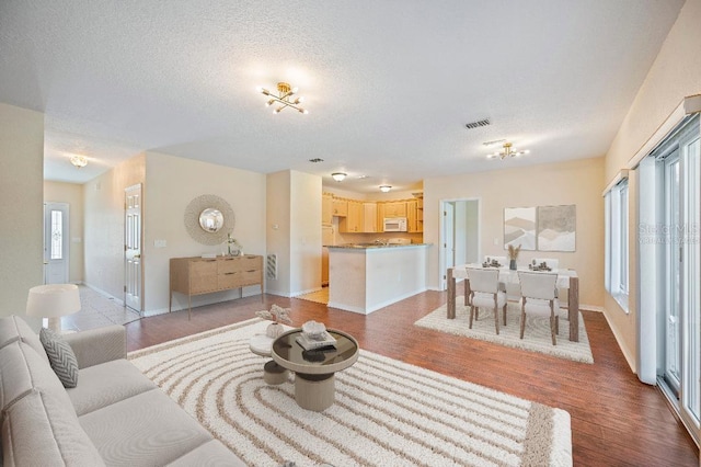 living area with a textured ceiling, baseboards, and light wood-type flooring
