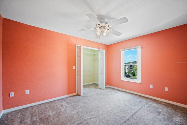 unfurnished bedroom with ceiling fan, carpet floors, baseboards, a closet, and a textured wall