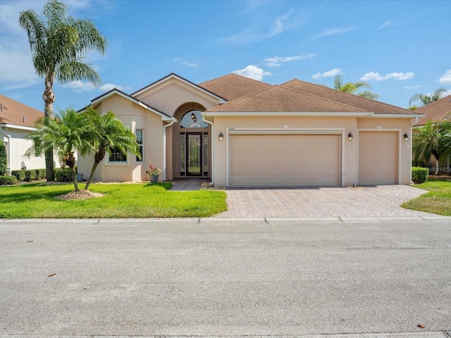 single story home featuring stucco siding, decorative driveway, a front yard, and a garage