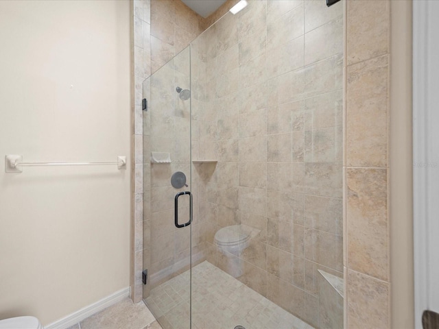 full bathroom featuring toilet, a stall shower, and baseboards