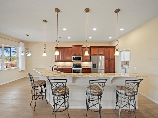 kitchen with a sink, brown cabinets, a breakfast bar, baseboards, and appliances with stainless steel finishes