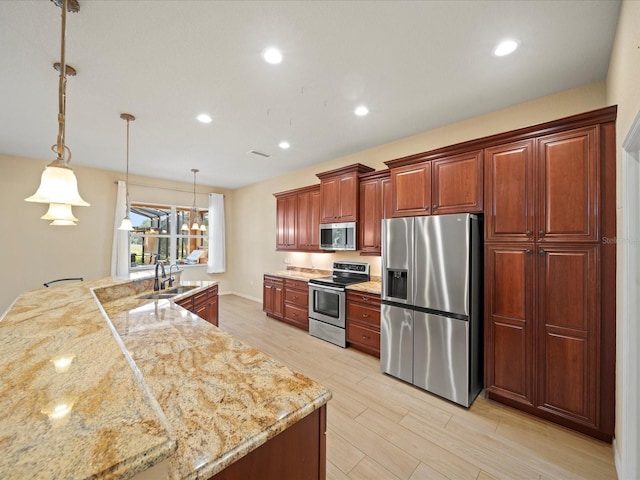kitchen featuring light wood-style flooring, a sink, appliances with stainless steel finishes, recessed lighting, and hanging light fixtures