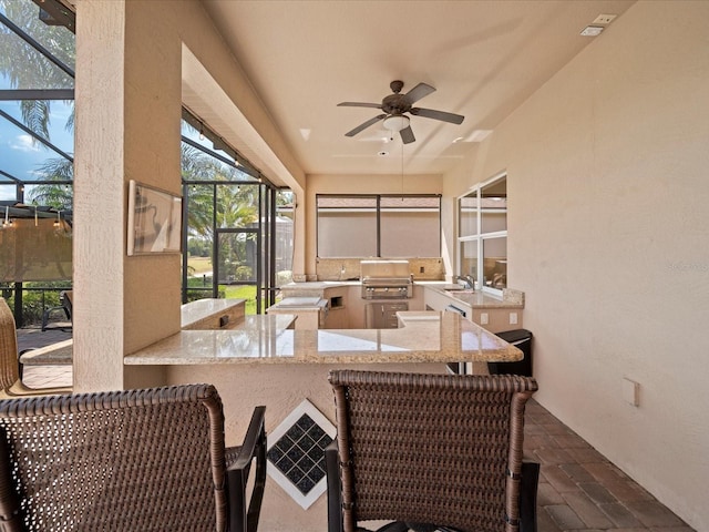 sunroom / solarium with a sink, ceiling fan, outdoor wet bar, and an outdoor kitchen