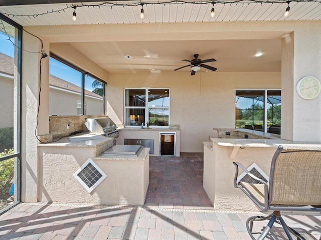 view of patio with exterior kitchen, a ceiling fan, outdoor wet bar, grilling area, and beverage cooler