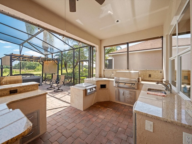 sunroom / solarium featuring a wealth of natural light, area for grilling, a ceiling fan, and a sink