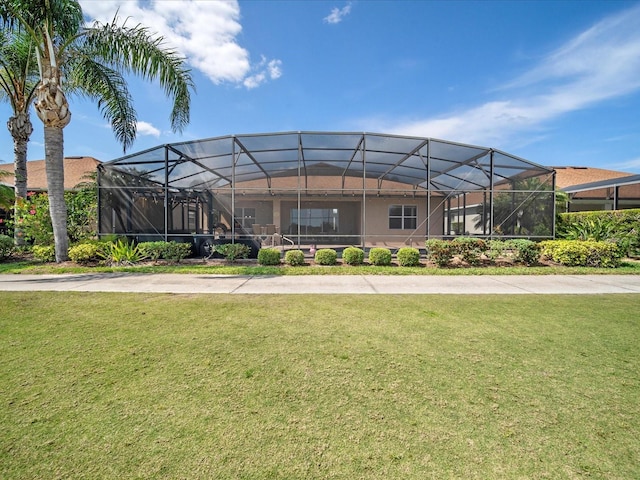 view of front of property featuring glass enclosure and a front yard