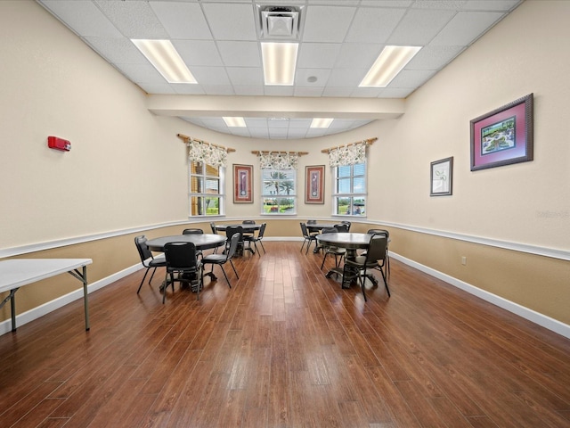 rec room with a drop ceiling, wood finished floors, and baseboards