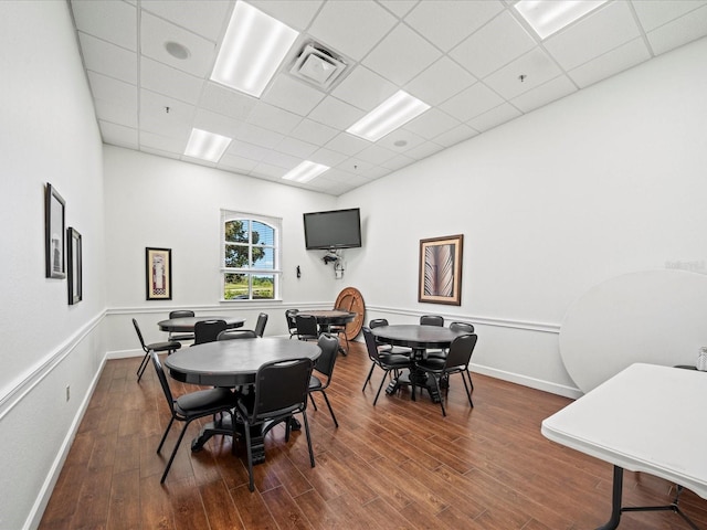 dining area featuring wood finished floors, visible vents, a drop ceiling, and baseboards
