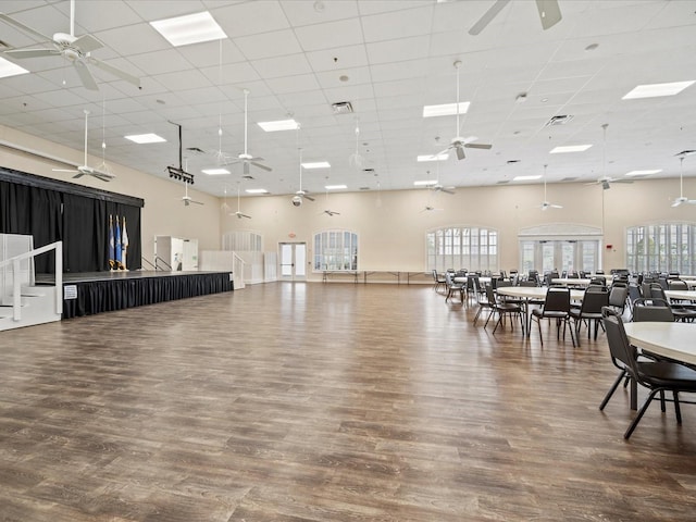 misc room with a towering ceiling, a drop ceiling, wood finished floors, and a ceiling fan