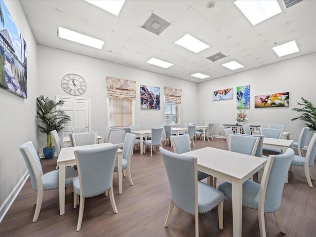 dining room with baseboards, wood finished floors, and a drop ceiling