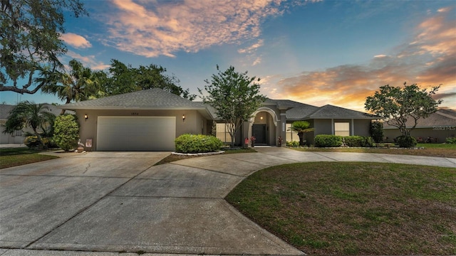 view of front of home featuring a garage, stucco siding, driveway, and a front lawn