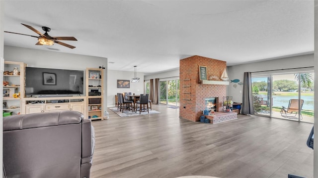 living area featuring a ceiling fan, wood finished floors, and a fireplace