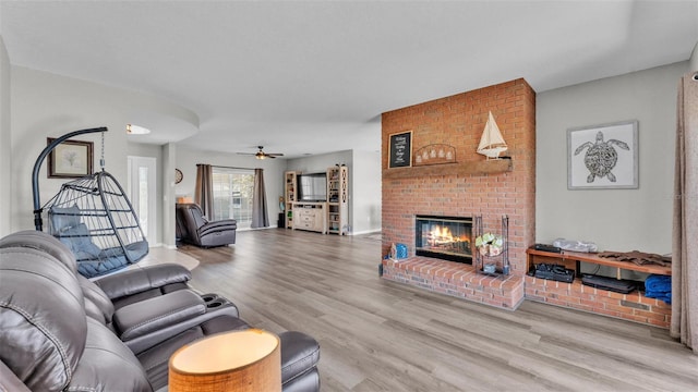 living room with a ceiling fan, wood finished floors, and a fireplace