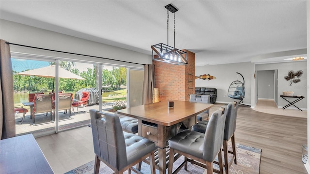 dining space with baseboards, light wood-style flooring, and a chandelier