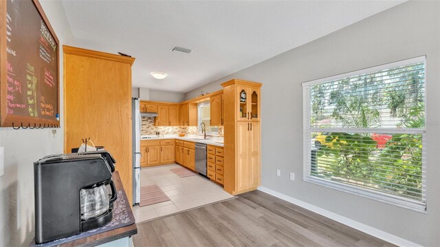 kitchen featuring visible vents, decorative backsplash, light wood-style floors, a sink, and appliances with stainless steel finishes