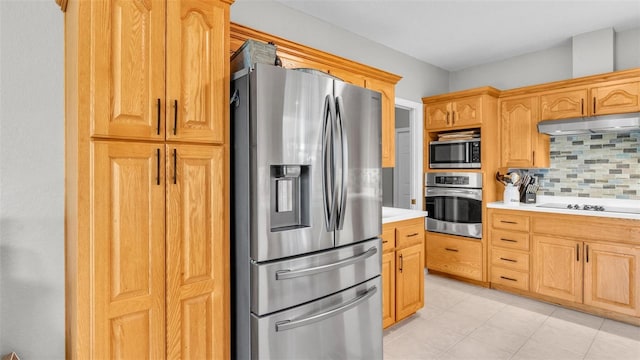 kitchen with light countertops, stainless steel appliances, decorative backsplash, light tile patterned floors, and under cabinet range hood