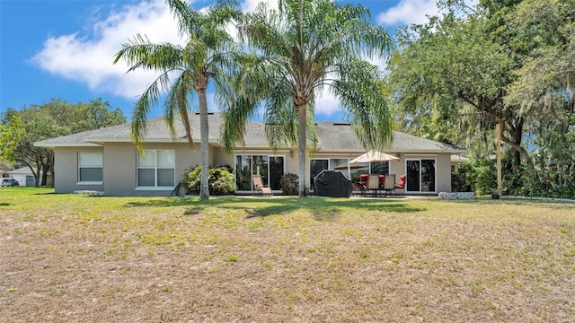 rear view of property featuring a yard, a patio area, and stucco siding