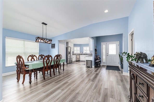 dining room featuring light wood-style floors, baseboards, an inviting chandelier, and lofted ceiling