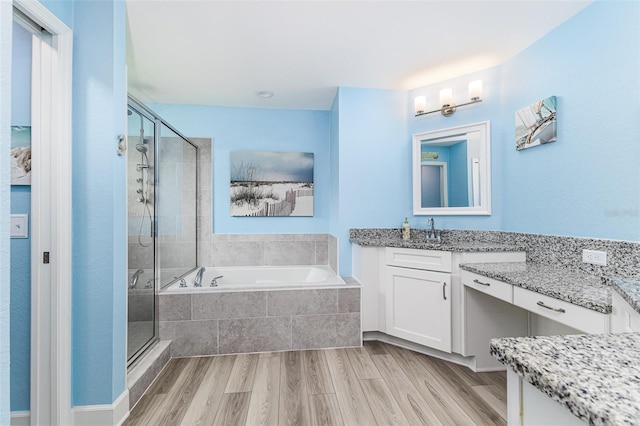 bathroom with a shower stall, wood finished floors, a bath, and vanity