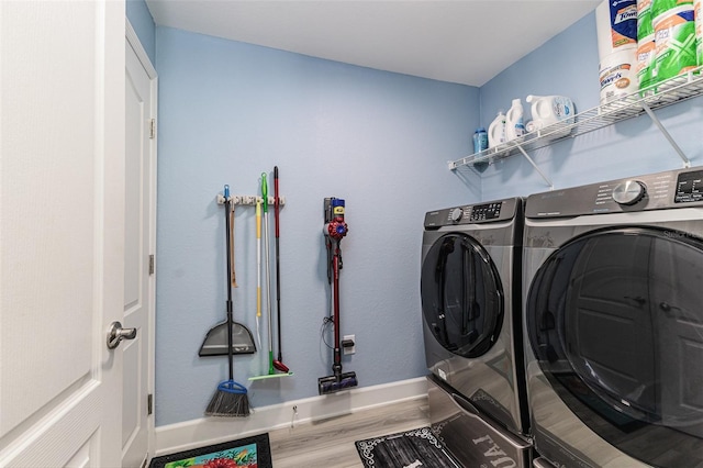 laundry room with laundry area, baseboards, wood finished floors, and washing machine and clothes dryer