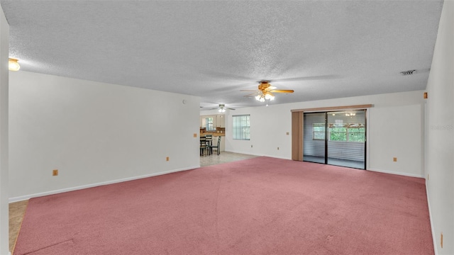 unfurnished living room featuring carpet flooring, a textured ceiling, a ceiling fan, baseboards, and visible vents