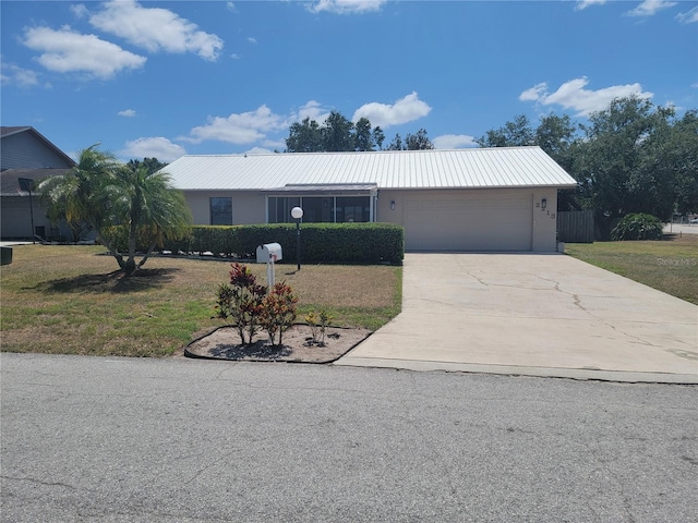ranch-style home featuring driveway, metal roof, a front yard, and a garage