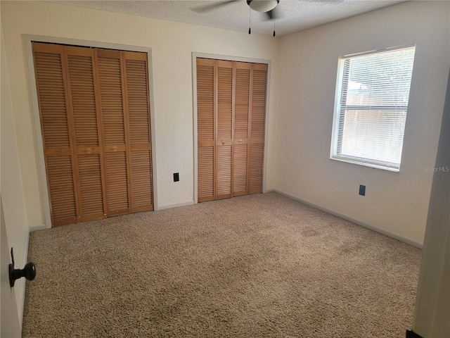 unfurnished bedroom featuring multiple closets, baseboards, and carpet