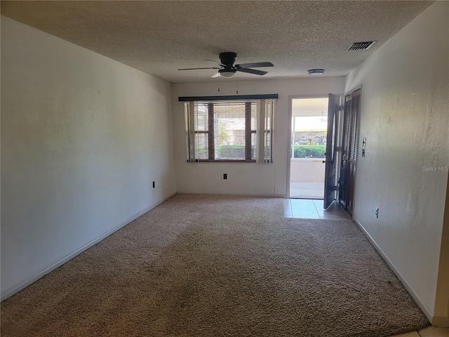 unfurnished room featuring light colored carpet, a ceiling fan, visible vents, and a textured ceiling