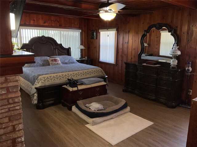 bedroom featuring wood ceiling, ceiling fan, wood finished floors, beamed ceiling, and wooden walls