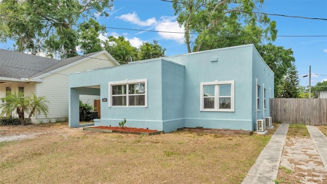 view of front of house with stucco siding, fence, and a front yard