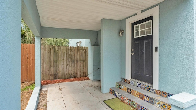 entrance to property with fence and stucco siding