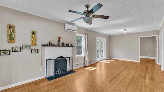 unfurnished living room with a brick fireplace, light wood-style floors, baseboards, ceiling fan, and a wall unit AC