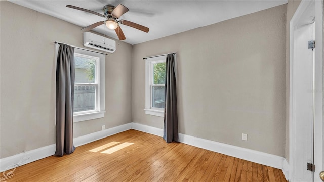 empty room with baseboards, a wall mounted air conditioner, a healthy amount of sunlight, and light wood-type flooring