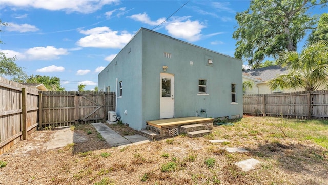 rear view of property featuring a fenced backyard, stucco siding, and a gate