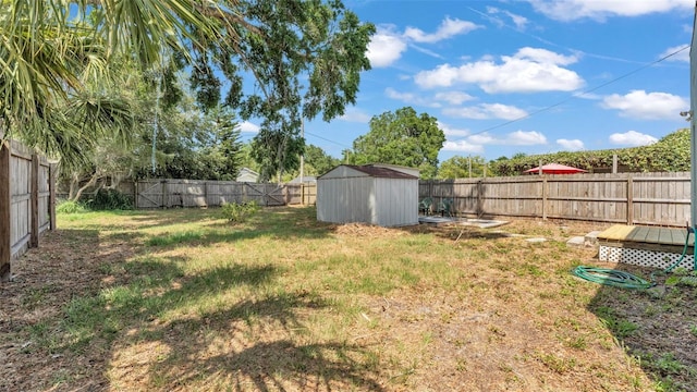 view of yard with an outdoor structure, a fenced backyard, and a shed