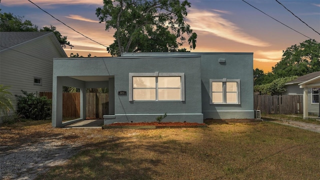view of front of property featuring fence, stucco siding, and a yard