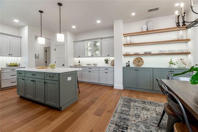527 W Park St, Lakeland, FL 33803 - kitchen featuring backsplash, open shelves, light countertops, light wood-type flooring, and gray cabinets