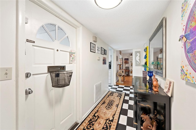 hall featuring a textured ceiling, tile patterned floors, and visible vents