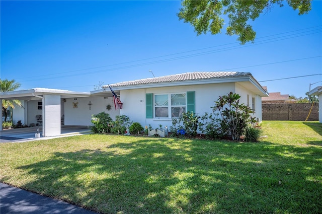 ranch-style house featuring fence, a front yard, stucco siding, an attached carport, and a tiled roof