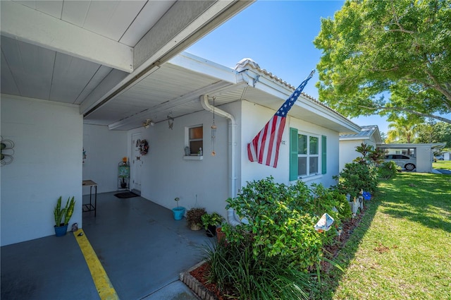view of side of property featuring stucco siding, a yard, a tile roof, and a carport