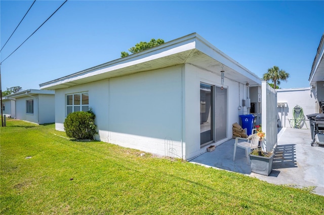 view of side of home with a patio and a yard