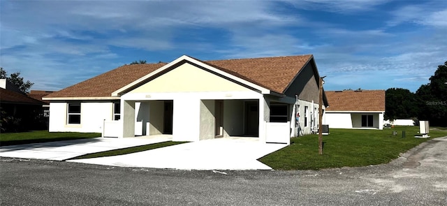 view of front of home featuring a front lawn, stucco siding, a shingled roof, central air condition unit, and driveway