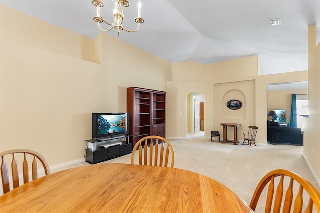 carpeted dining room with arched walkways, baseboards, an inviting chandelier, and high vaulted ceiling