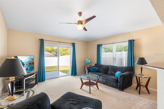 carpeted living area featuring baseboards, a ceiling fan, and a healthy amount of sunlight