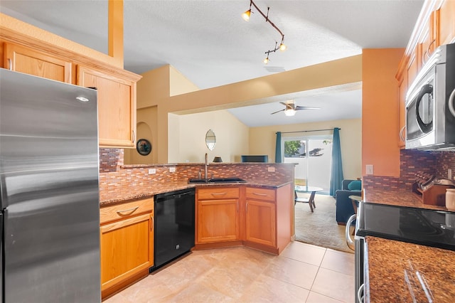 kitchen featuring a sink, a peninsula, tasteful backsplash, a ceiling fan, and stainless steel appliances
