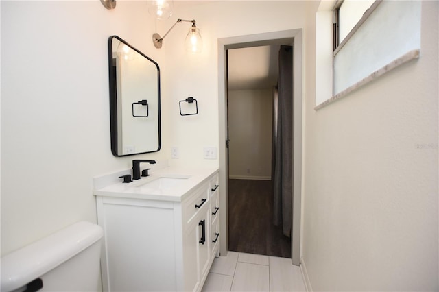 bathroom featuring toilet, tile patterned floors, baseboards, and vanity