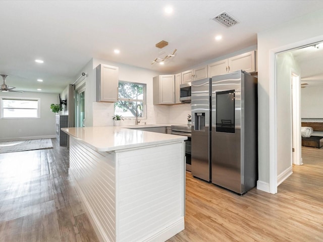 502 Duchess Dr, Lakeland, FL 33803 - kitchen featuring visible vents, light countertops, a peninsula, light wood-style floors, and stainless steel appliances